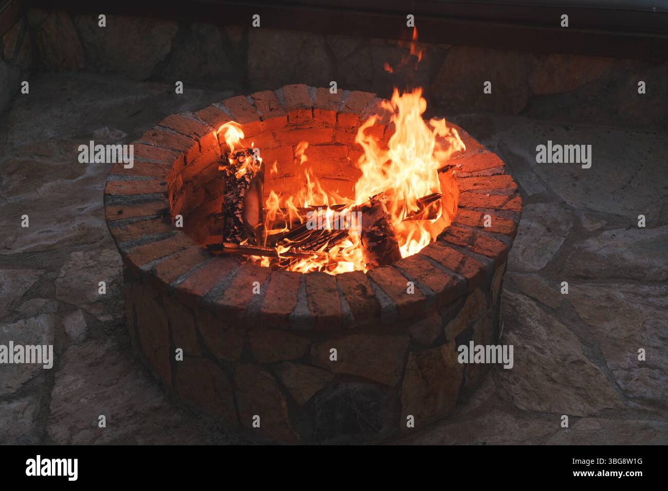 Ein warmes Feuer brennt in einer stilvollen Feuerstelle in einem Luxushotel und schafft ein einladendes Abendambiente. Stockfoto