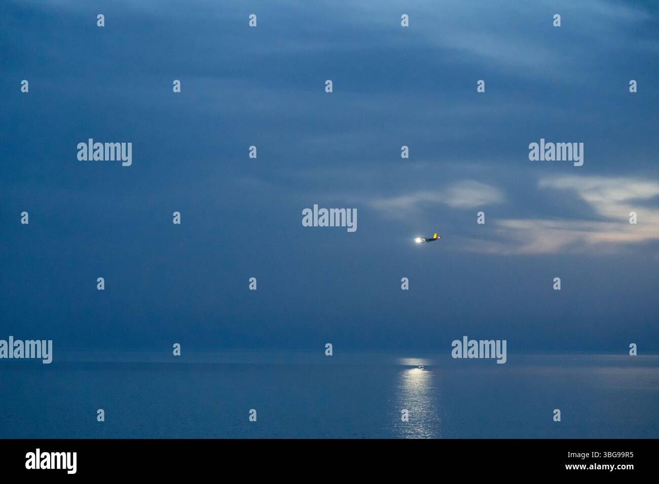 Ein Flugzeug, das nachts landet und über das Meer fliegt Stockfoto