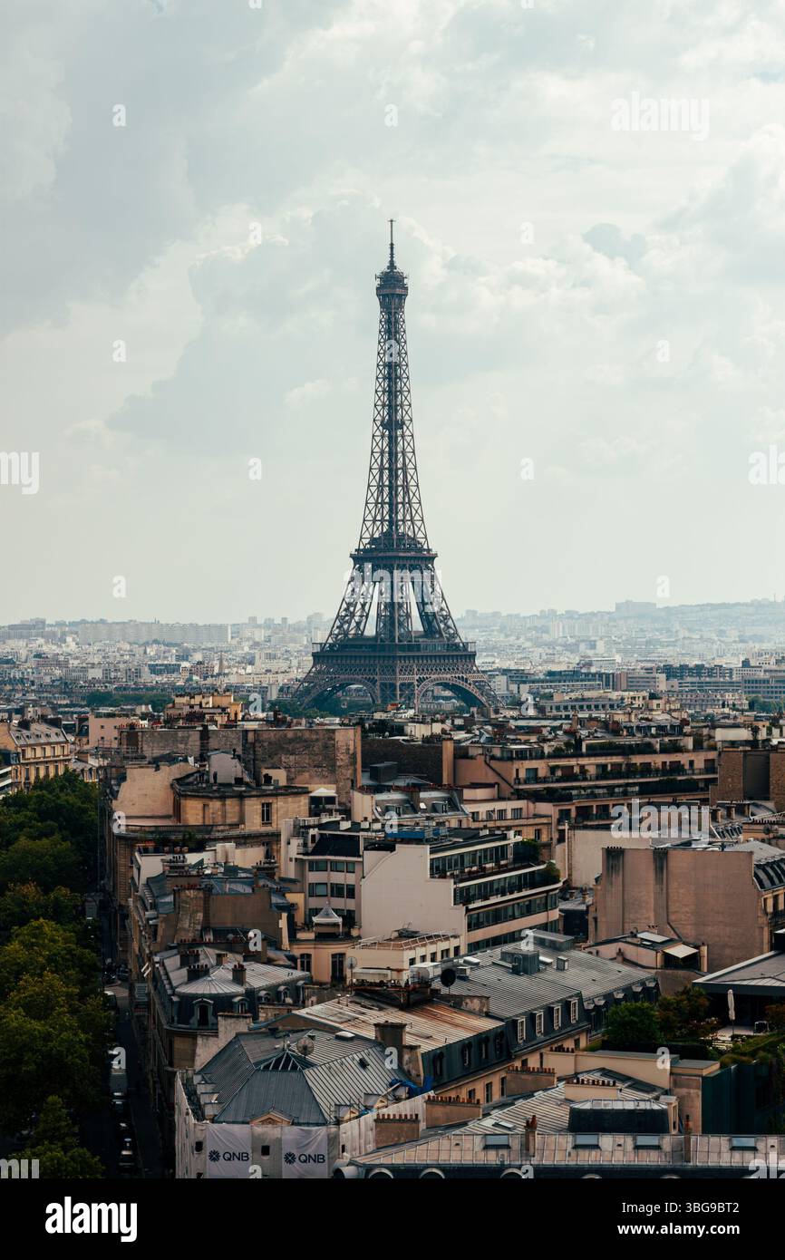 Der ikonische Eiffelturm erhebt sich über dem weitläufigen Stadtbild von Paris unter einem bewölkten Himmel. Stockfoto