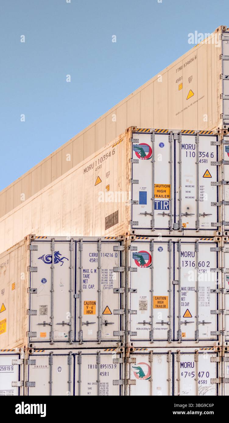 Ein riesiger Stapel weißer Schiffscontainer steht unter einem hellblauen Himmel ohne Wolken Stockfoto