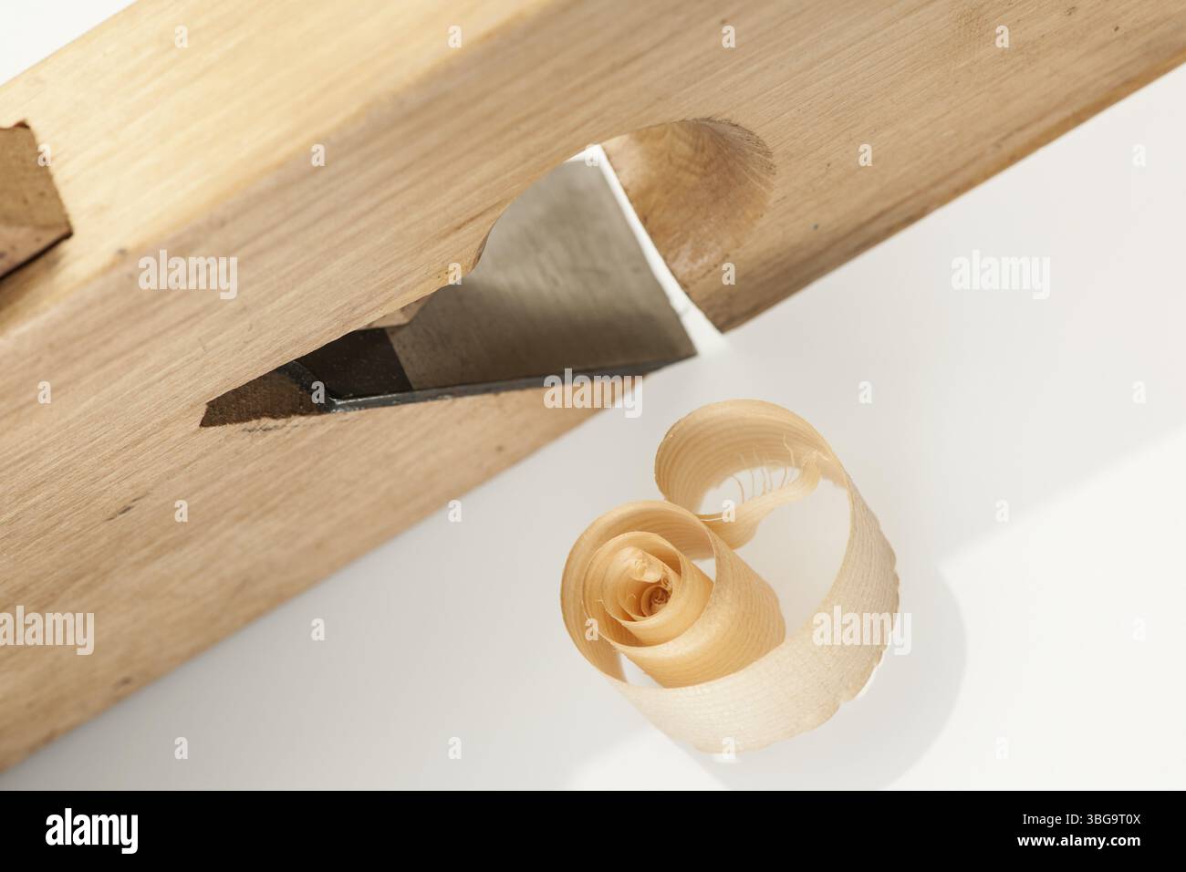 Hochwinkelansicht eines gerollten Holzschnitzes, der auf einem weißen Atelierhintergrund neben einer Felgenebene liegt Stockfoto
