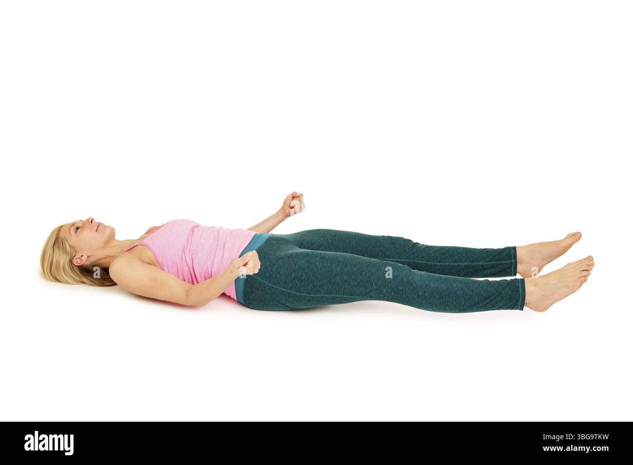 Flach angewinkelte Ganzkörperseitenansicht einer jungen Frau, die auf dem Rücken in einer Variation der Yogaposition (Shavasana) auf weißem Hintergrund liegt Stockfoto