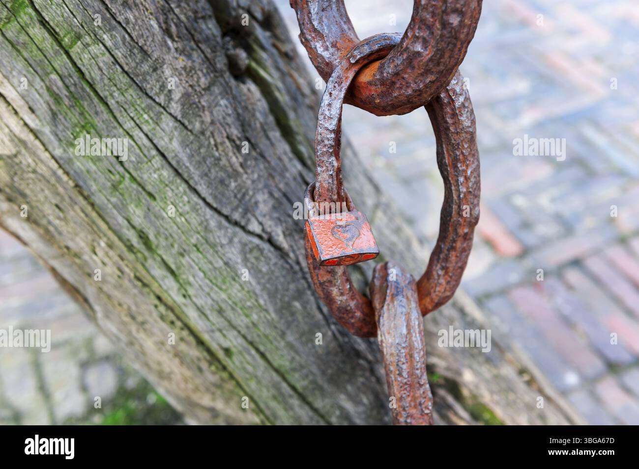 Nahaufnahme eines kleinen Vorhängeschlosses mit Herz an einer alten verwitterten Ankerkette im Hafen von Carolinensiel in Ostfriesland Stockfoto