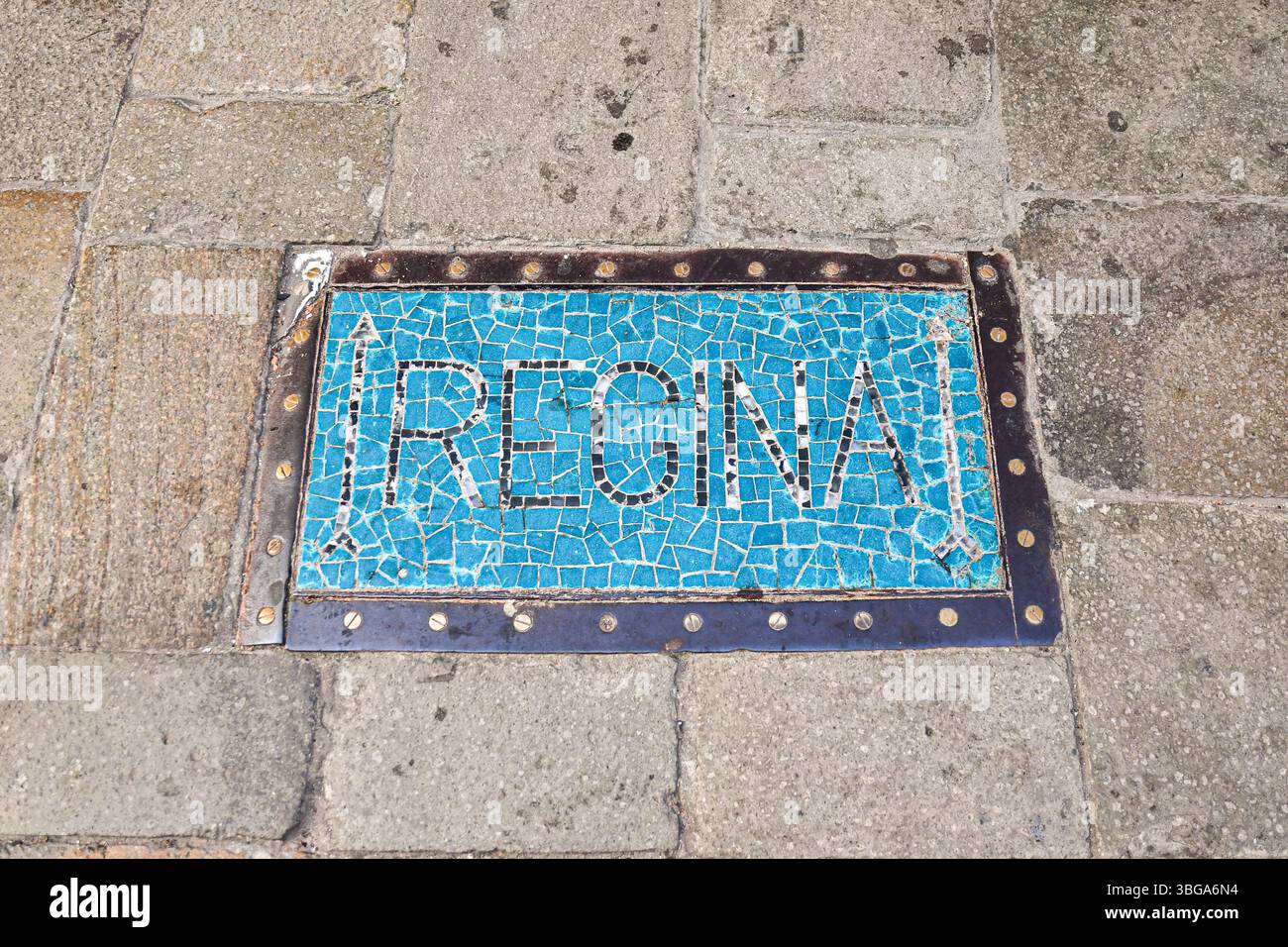 Blick von oben auf ein altes Richtungsschild auf einem Straßenpflaster, dekoriert mit einem Glasmosaik mit der Aufschrift „Regina“, Venedig, Venetien, Italien Stockfoto