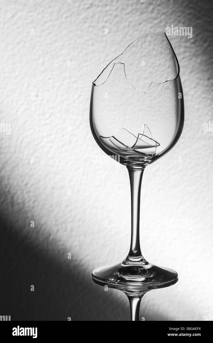 Atelier-Nahaufnahme eines zerbrochenen Weinglases mit gebrochenen Fragmenten vor dem Helligkeitsgradienten im Hintergrund Stockfoto