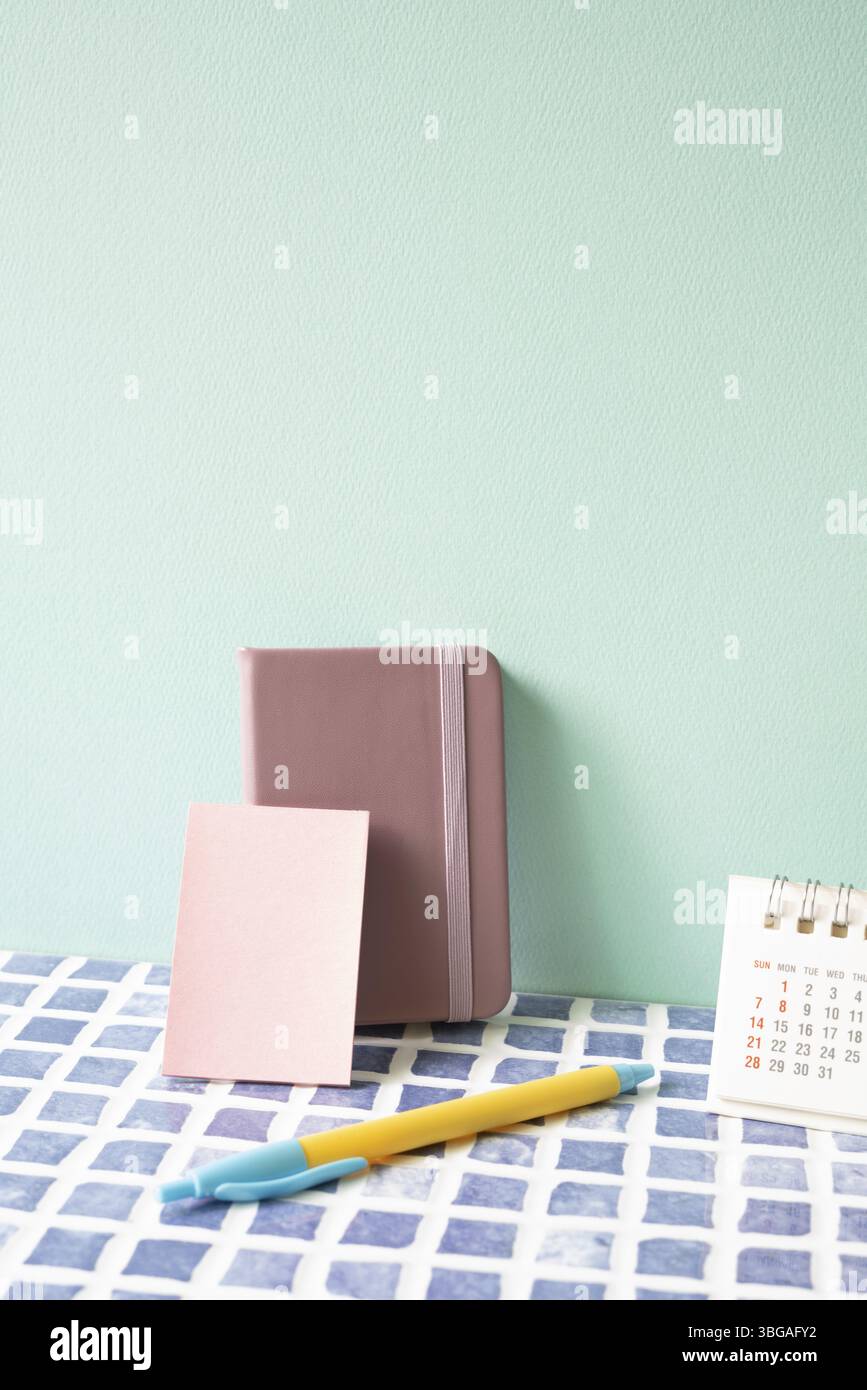 Tagebuchnotiz, Stift und Kalender auf blau gefliestem Schreibtisch. Mint. Wandhintergrund. Arbeitsbereich Stockfoto