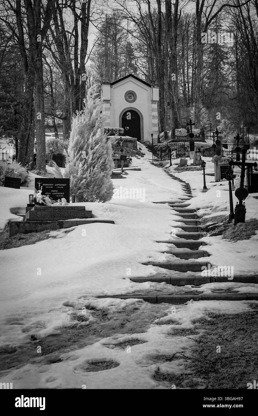 Verschneite Treppen zur Kapelle auf dem Friedhof in der Nähe der Kirche in Tatranska Javorina im Winter Stockfoto