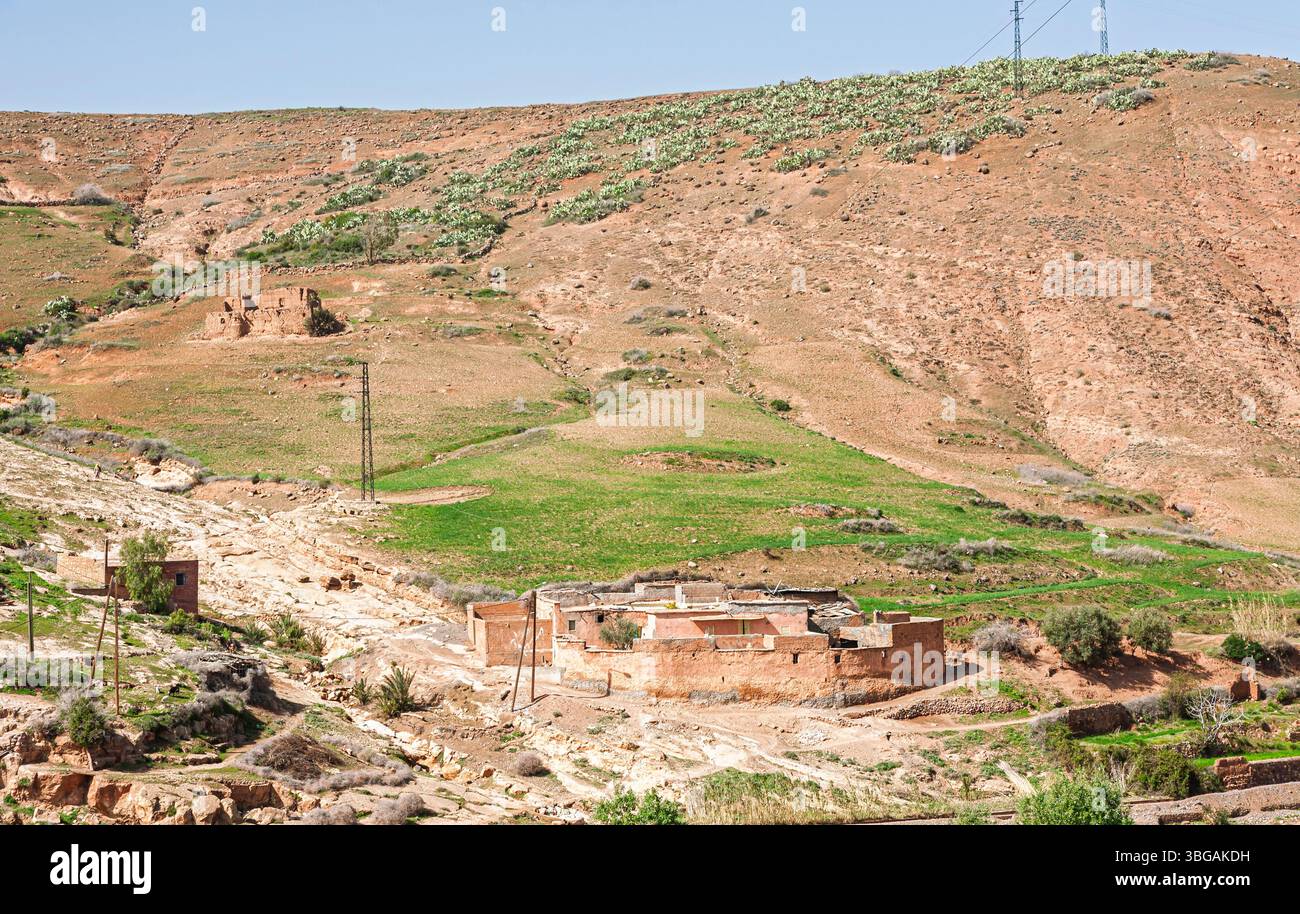 Rote Backsteinhöfe, einige Ruinen, eines Berberdorfes auf einem Hügel in einer trockenen, trockenen Landschaft im Hohen Atlasgebirge, Marokko Stockfoto