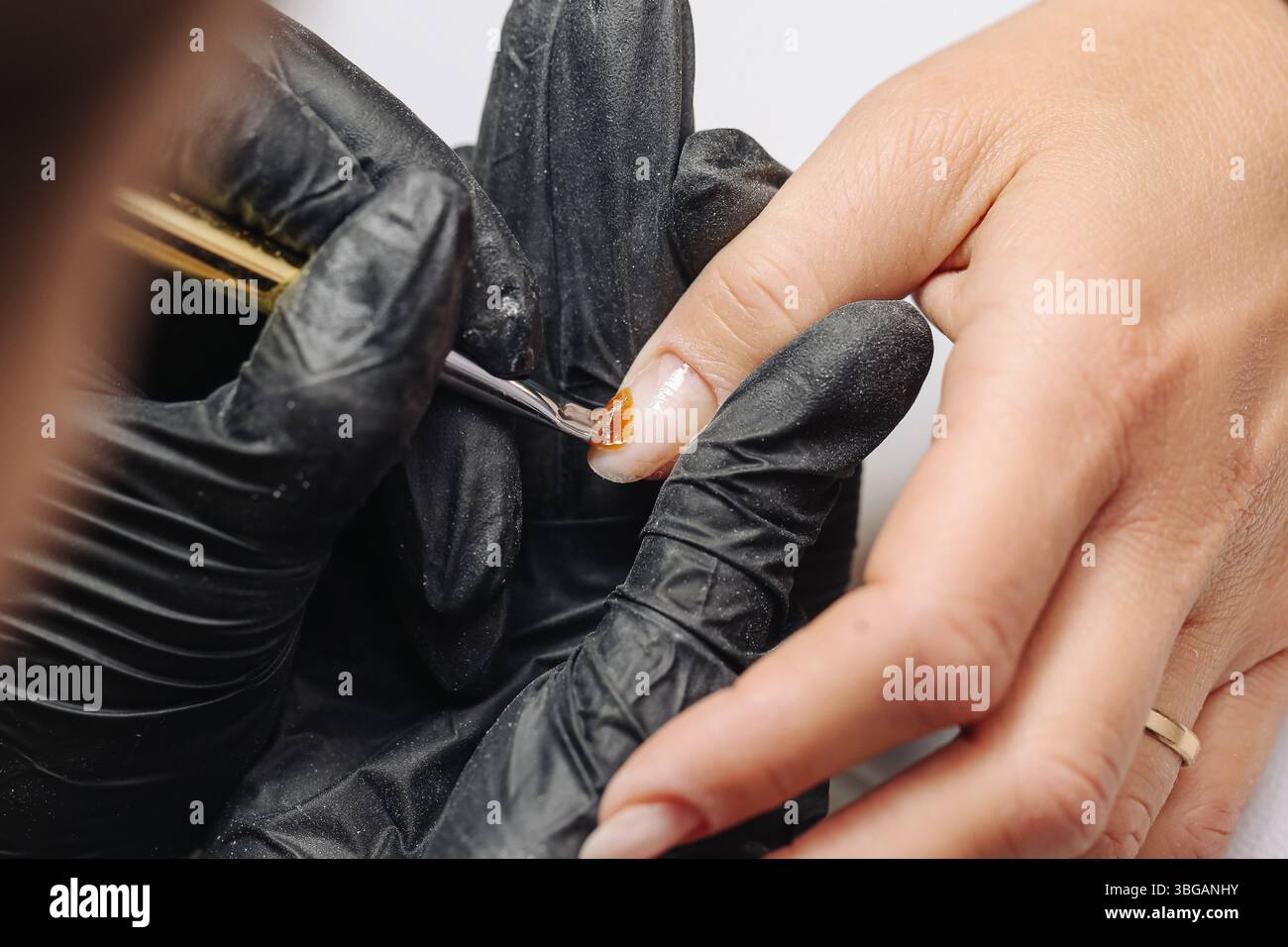 Maniküre mit schwarzen Handschuhen. nagellackauftragen durch Schönheitsexperten. Nahaufnahme von Pinselmalerei-Fingernägeln. Handpflege und Schönheit. Stockfoto