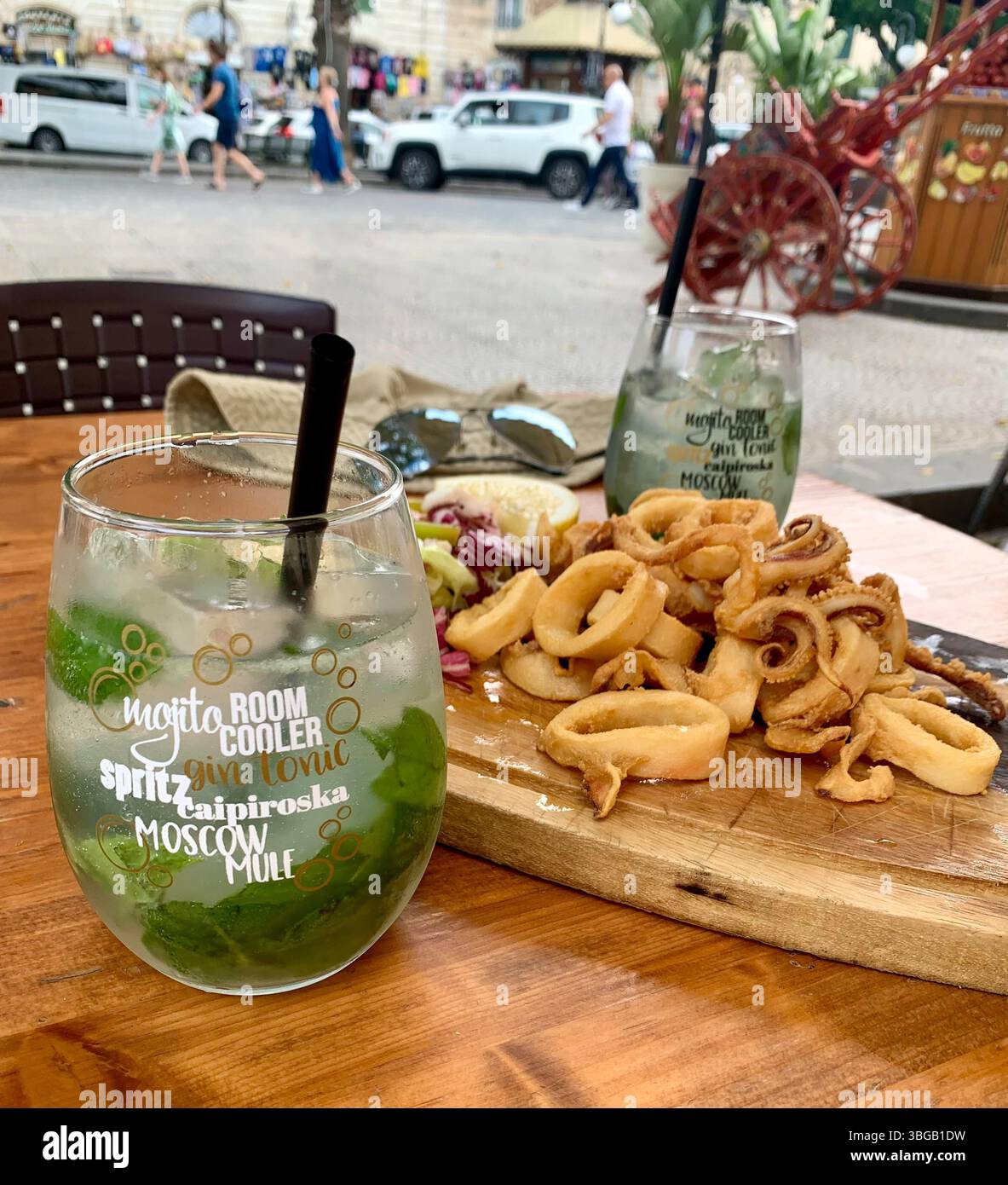 Knusprige Calamari mit Salat und erfrischendem jungfräulichem Mojito in Ortigia, Sizilien Stockfoto