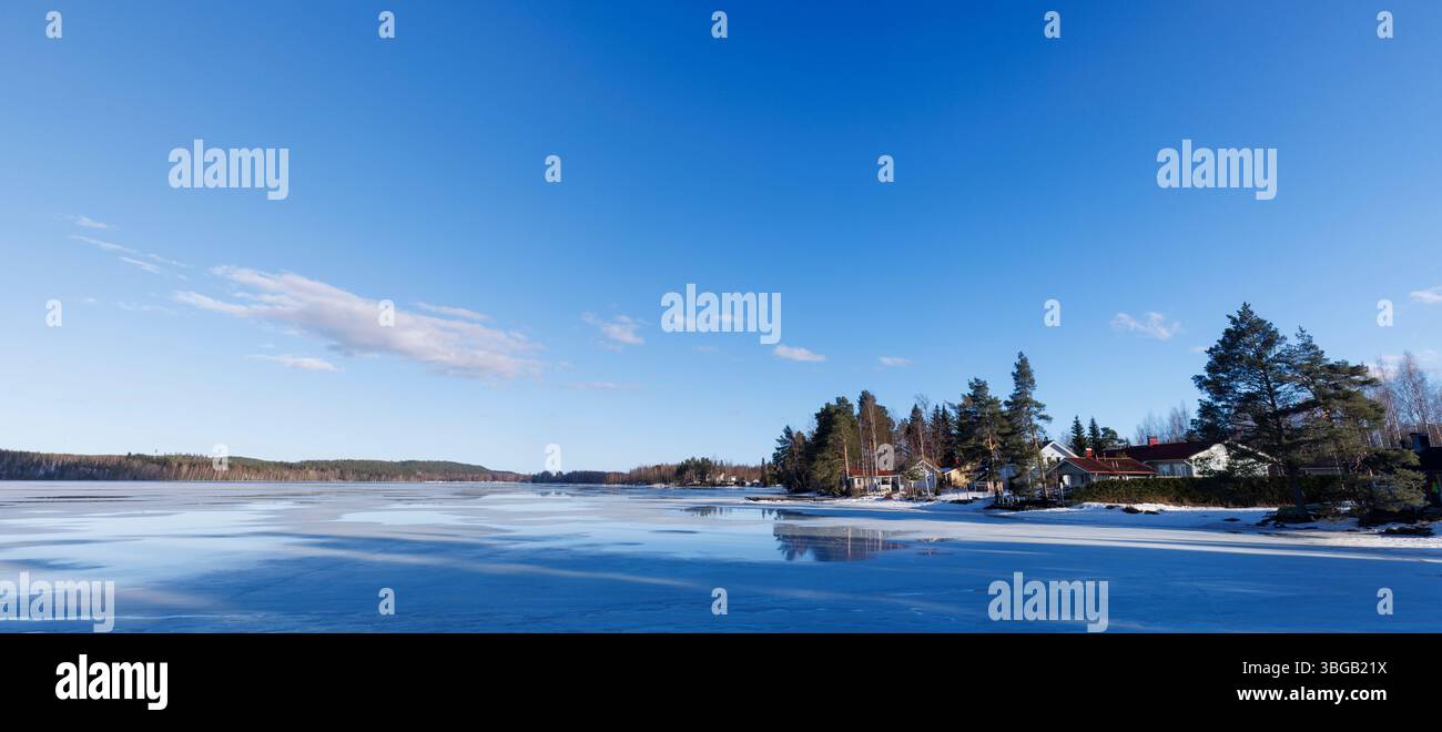 Einfamilienhäuser am gefrorenen Iisvesi-See im Frühling, Finnland Stockfoto