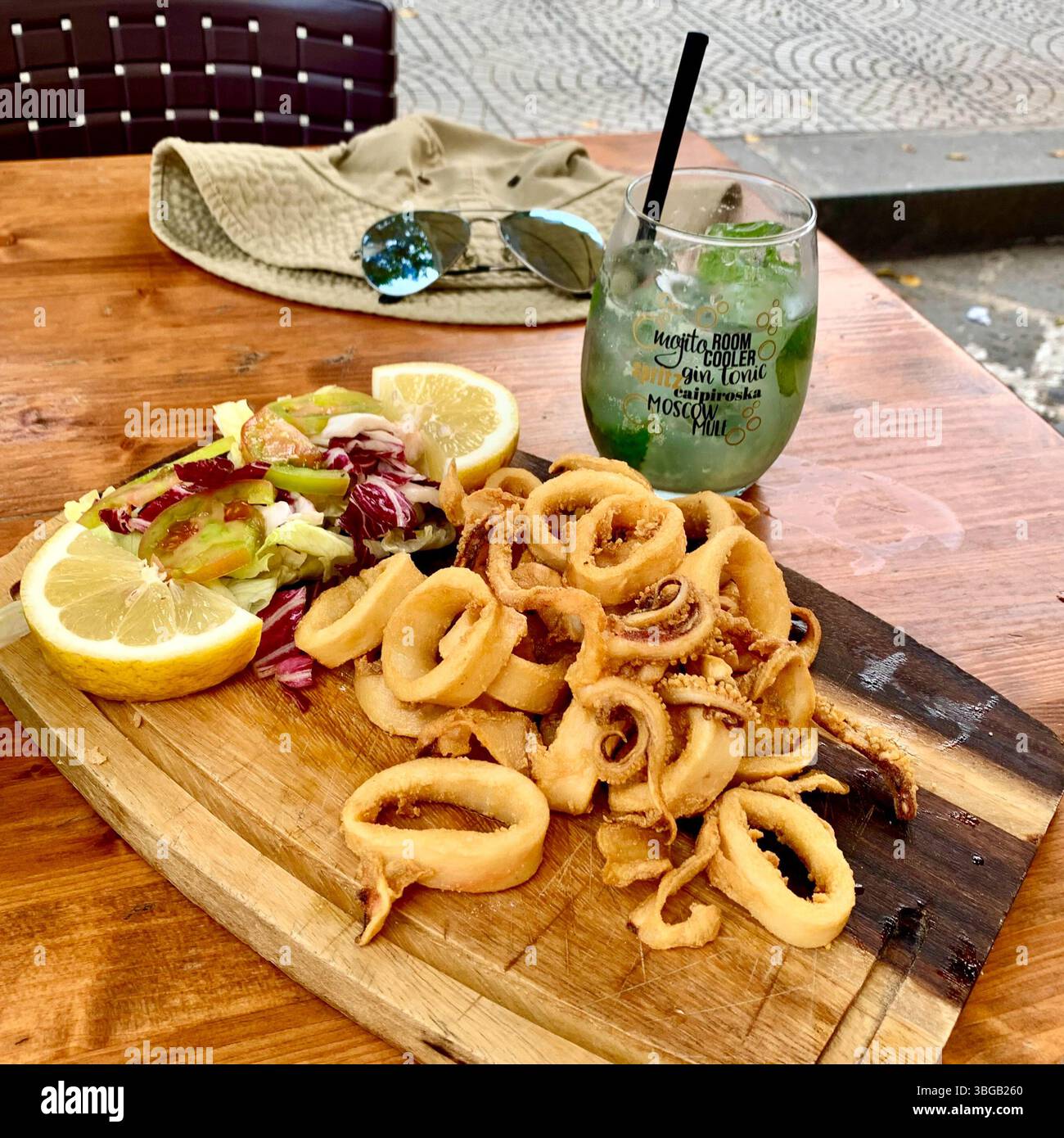 Knusprige Calamari mit Salat und erfrischendem Mojito-Cocktail Stockfoto