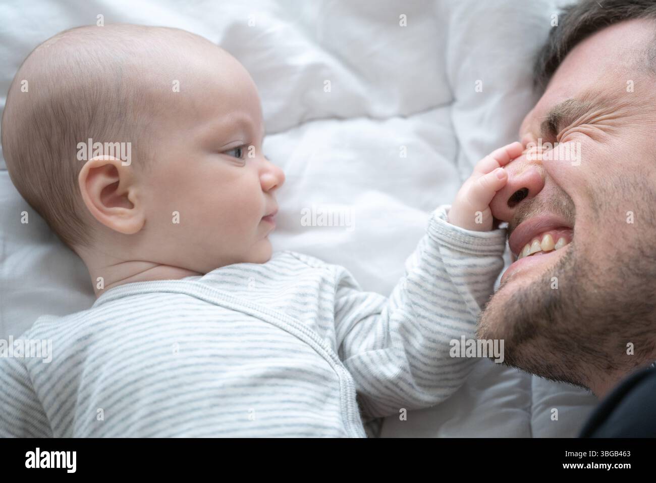 Ein zärtlicher Moment: Die sanfte Berührung eines Babys weckt eine emotionale Verbindung. Aufgenommen auf einem hellen, weichen Hintergrund, der ein Gefühl der Sicherheit weckt Stockfoto