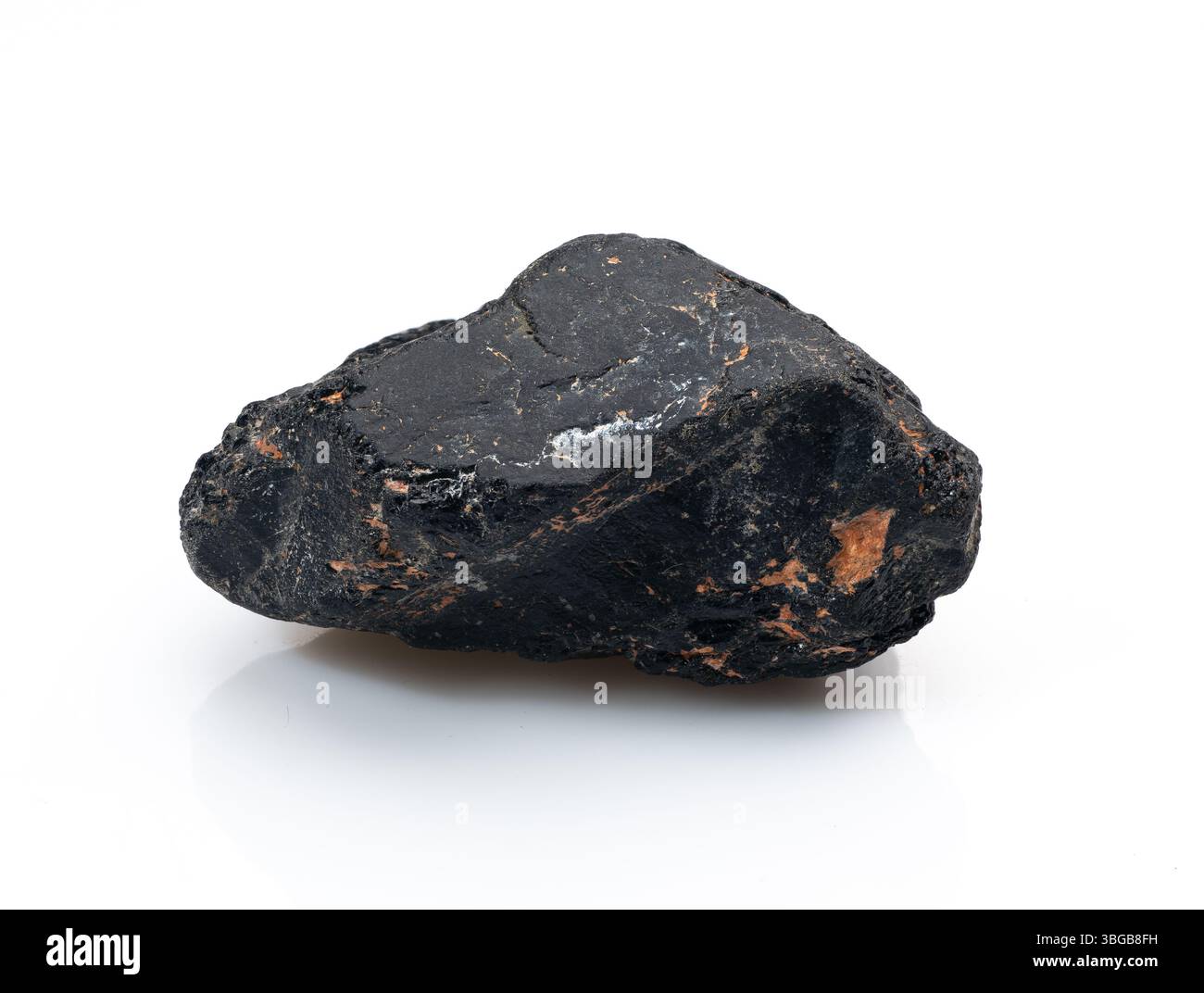 Bei einer Nahaufnahme wird ein dunkler, raukantiger schwarzer Turmalin-Kristallstein auf einer sauberen weißen Oberfläche gezeigt, ideal für geologische Studien oder ganzheitliche Schreie Stockfoto