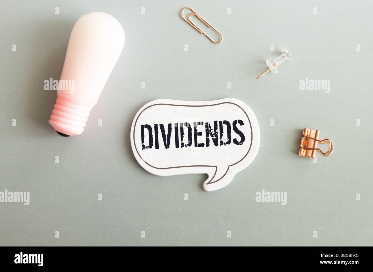 Ein Fetzen blaues Papier mit Clips auf grauem Hintergrund mit den DIVIDENDEN. Stockfoto