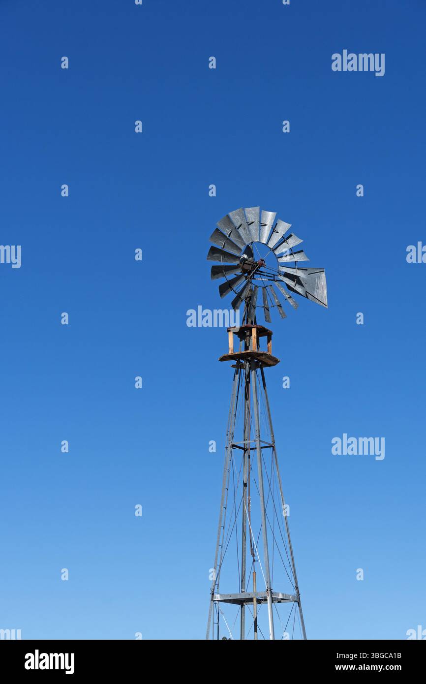 Galvanisierte Metallwindmühle für einen Brunnen mit blauem Himmel Hintergrund und Copyspace Stockfoto