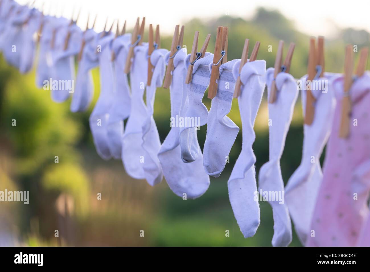 Babysocken in verschiedenen Pastelltönen hängen im Freien und spiegeln Familienroutinen, sanftes Leben, Minimalismus und Bio-Pflege in einem sauberen und sauberen Ambiente wider Stockfoto