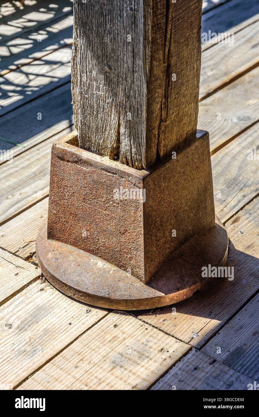 Schützender gusseiserner Fuß, der einen Holzpfosten auf dem beplankten Deck stützt - Zentralfrankreich. Stockfoto