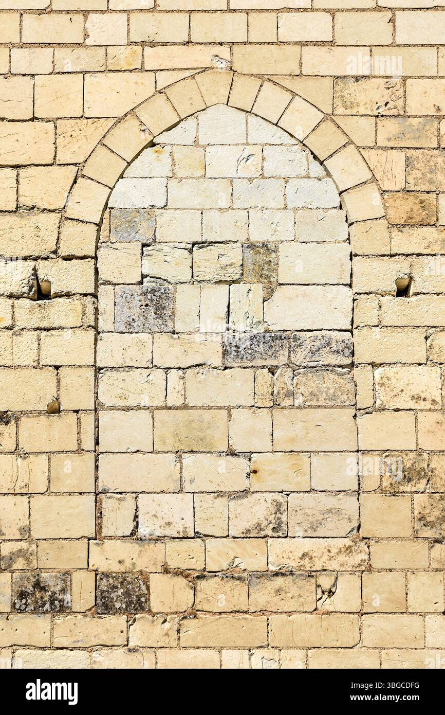 Ausgefülltes bogenförmiges Fenster öffnet sich in der Wand der Kirche - Zentralfrankreich. Stockfoto