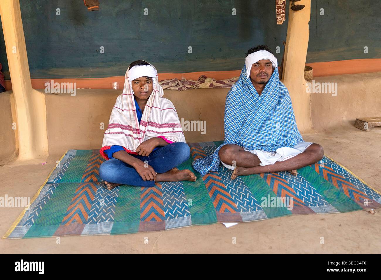 Bräutigam und sein jüngerer Bruder in traditioneller Kleidung warten auf eine Hochzeitszeremonie vor einem Lehmhaus in orissa in indien Stockfoto