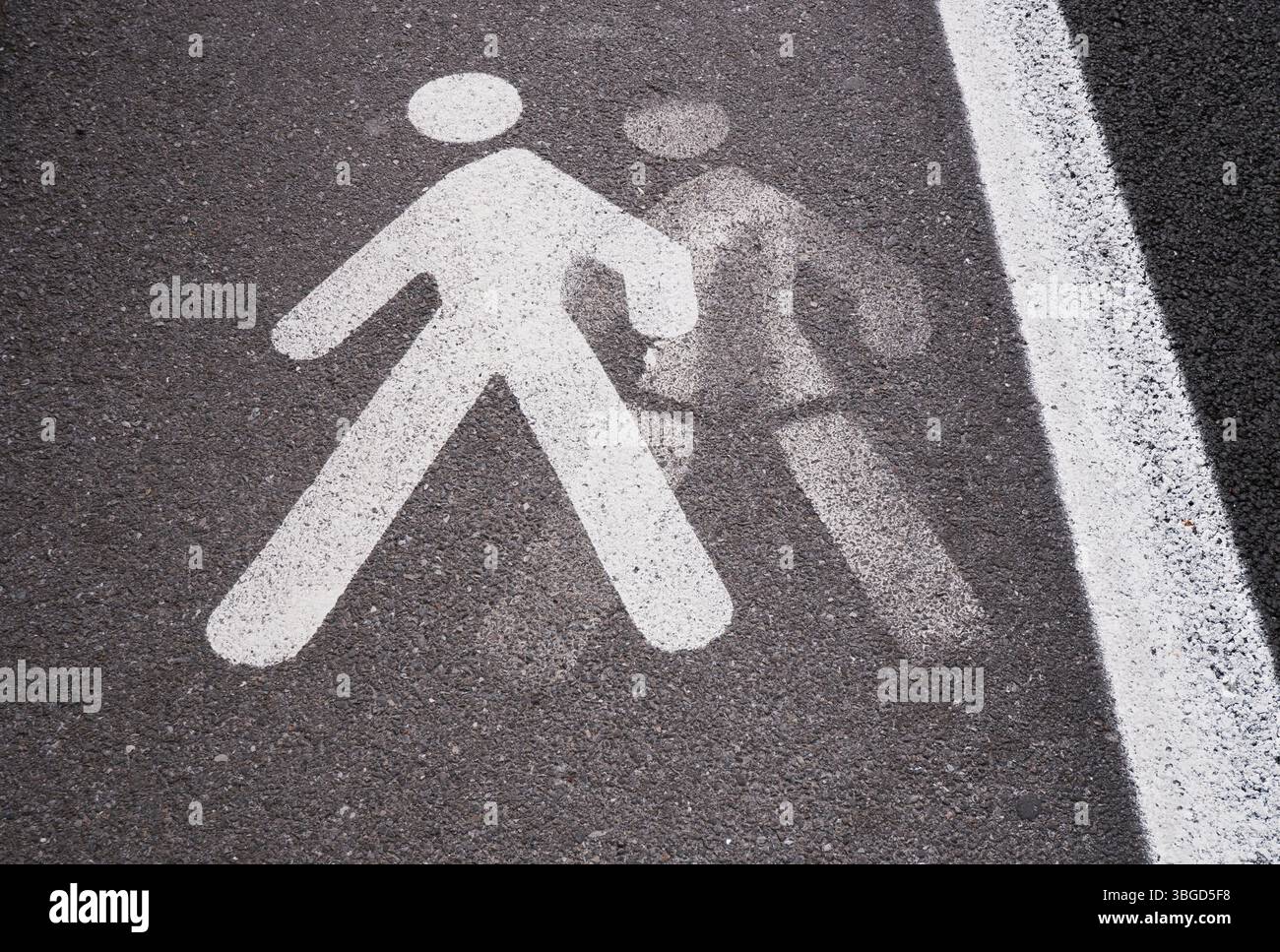 Alte und neu weiß lackierte Fußgängerfigur auf Asphalt Stockfoto