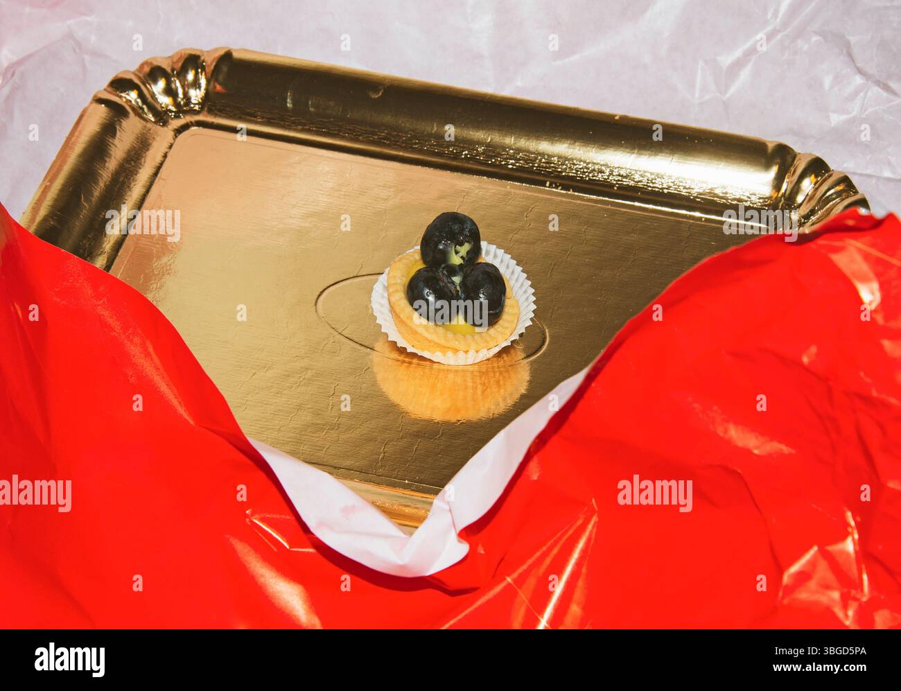 Ein einzelner Teig mit Trauben in einer goldenen Pappschale Stockfoto