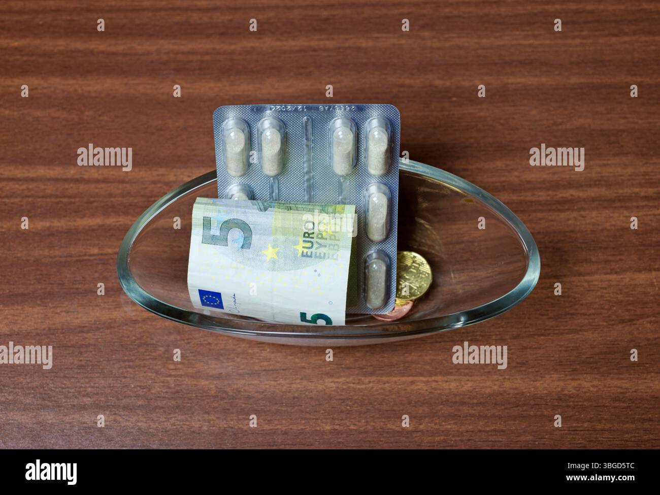 Pillen und Euro-Ersatzgeld in einer Glasschleife auf dem Tisch Stockfoto