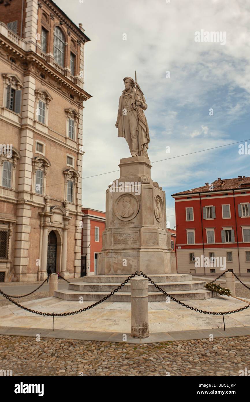 Modena, Italien 1. Januar 2025: Steinstatue des ciro menotti, italienischer Patriot, mit einer Flagge auf der piazza roma, modena, mit herzoglichem Palast im Hintergrund Stockfoto