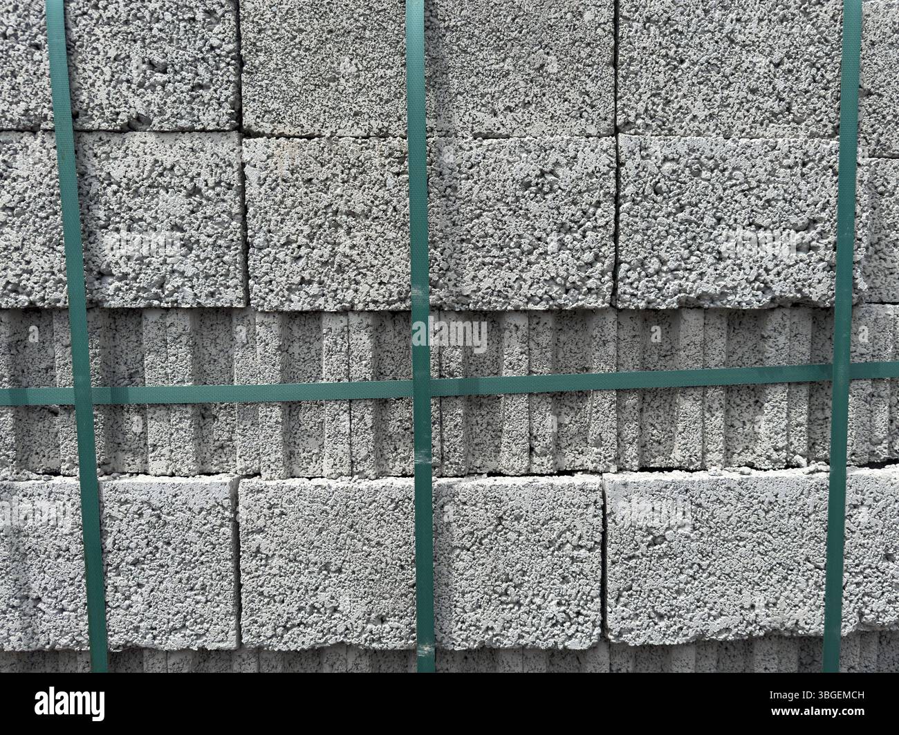 Stapel grauer Porenbetonblöcke, dicht verpackt und mit grünen Bändern gesichert. Keine Personen. Nützlich für die Bauindustrie und den Hintergrund. Stockfoto