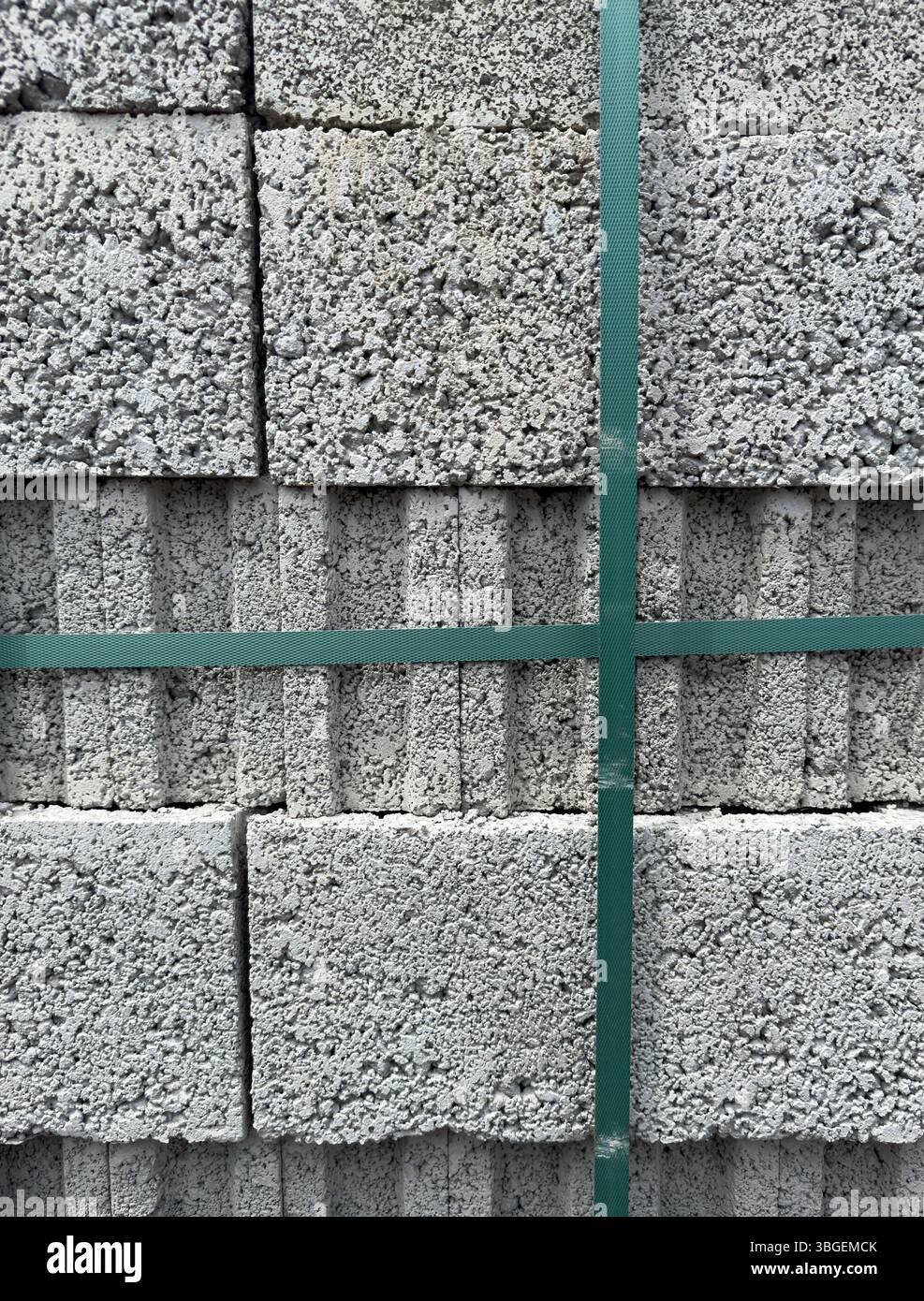 Stapel aus Porenbetonblöcken mit rauer Oberflächenstruktur, gesichert durch grüne Bänder, vertikale Ausrichtung. Ideal für Bau- und Industrieanwendungen Stockfoto