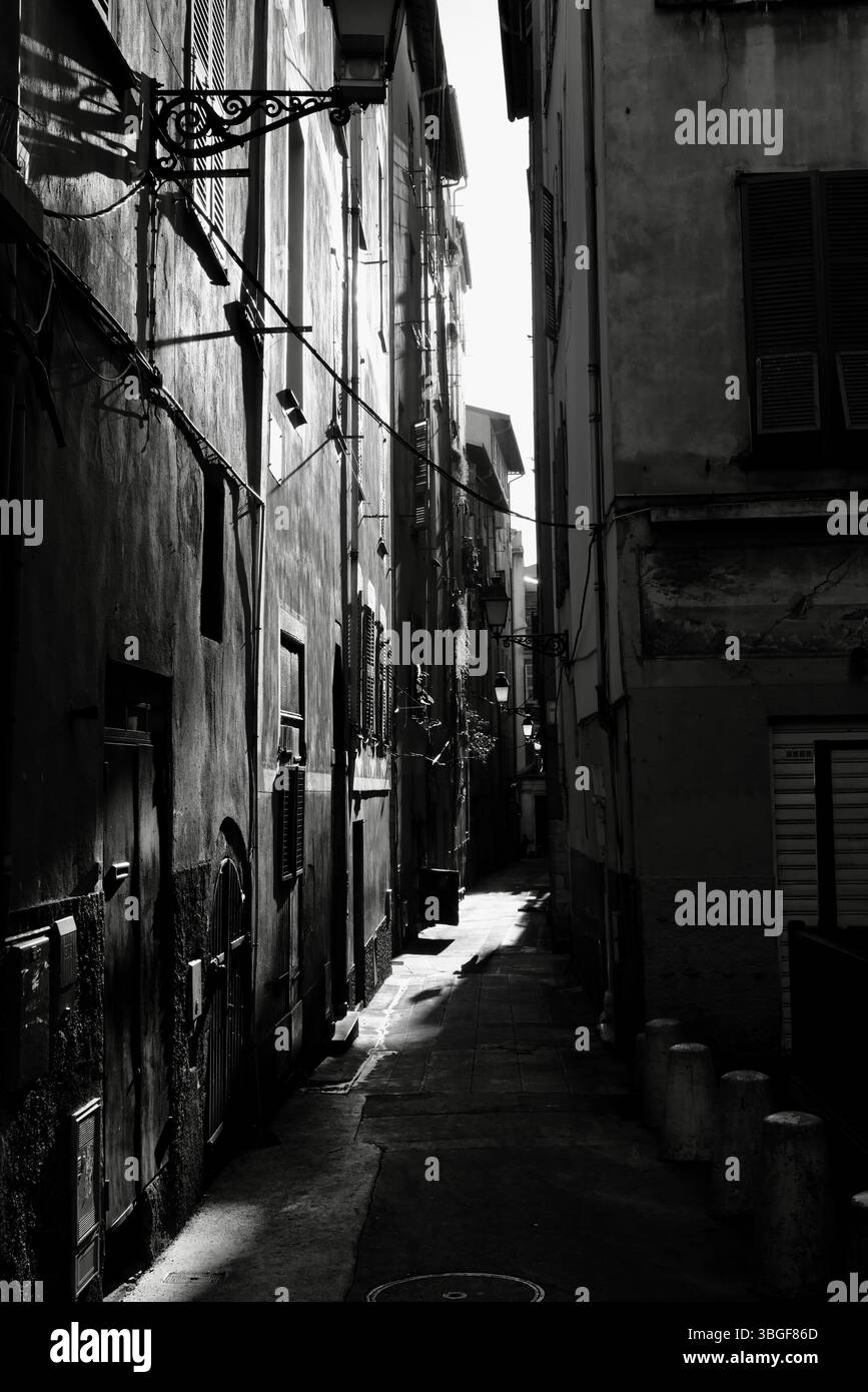 Enge Gasse in dramatischem Schwarz-weiß, mit starkem Sonnenlicht, das tiefe Schatten über alte europäische Gebäude wirft. Stockfoto