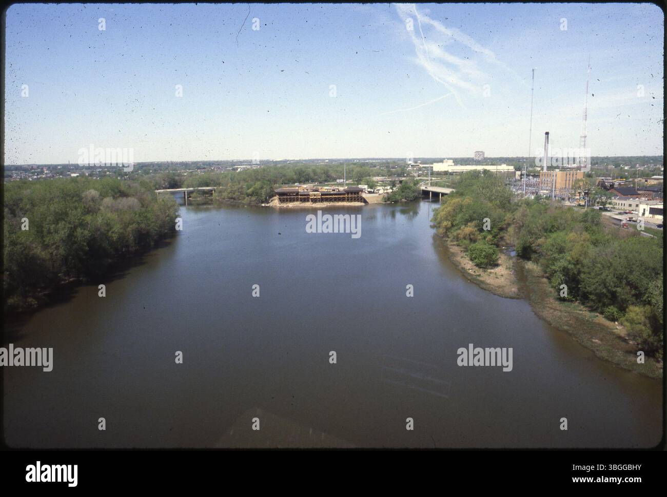 Ein Blick nach Westen von 1987 fängt den Zusammenfluss des Scioto River (links) und des Olentangy River (rechts) ein. Zentral im Bild befindet sich das Confluence Park Restaurant, das im Juli 1987 eröffnet wurde. Das United States Post Office am 850 Twin Rivers Drive, Summit Chase Condominiums an der 1000 Urlin Avenue, das alte Stadtlichtwerk und der rot-weiße WBNS-TV Channel 10 Sendeturm am 770 Twin Rivers Drive sind ebenfalls zu sehen. Stockfoto