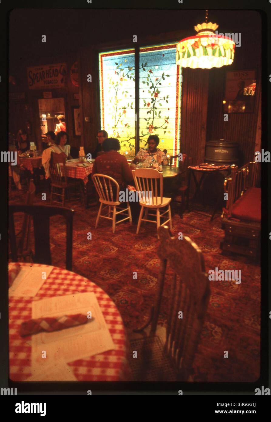 Blick von innen auf das Old Spaghetti Warehouse, mit Esstisch und Buntglasfenster. Das Restaurant wurde 1978 in einem ehemaligen Gebäude der City Ice and Coal Company in Columbus, Ohio, eröffnet. Stockfoto
