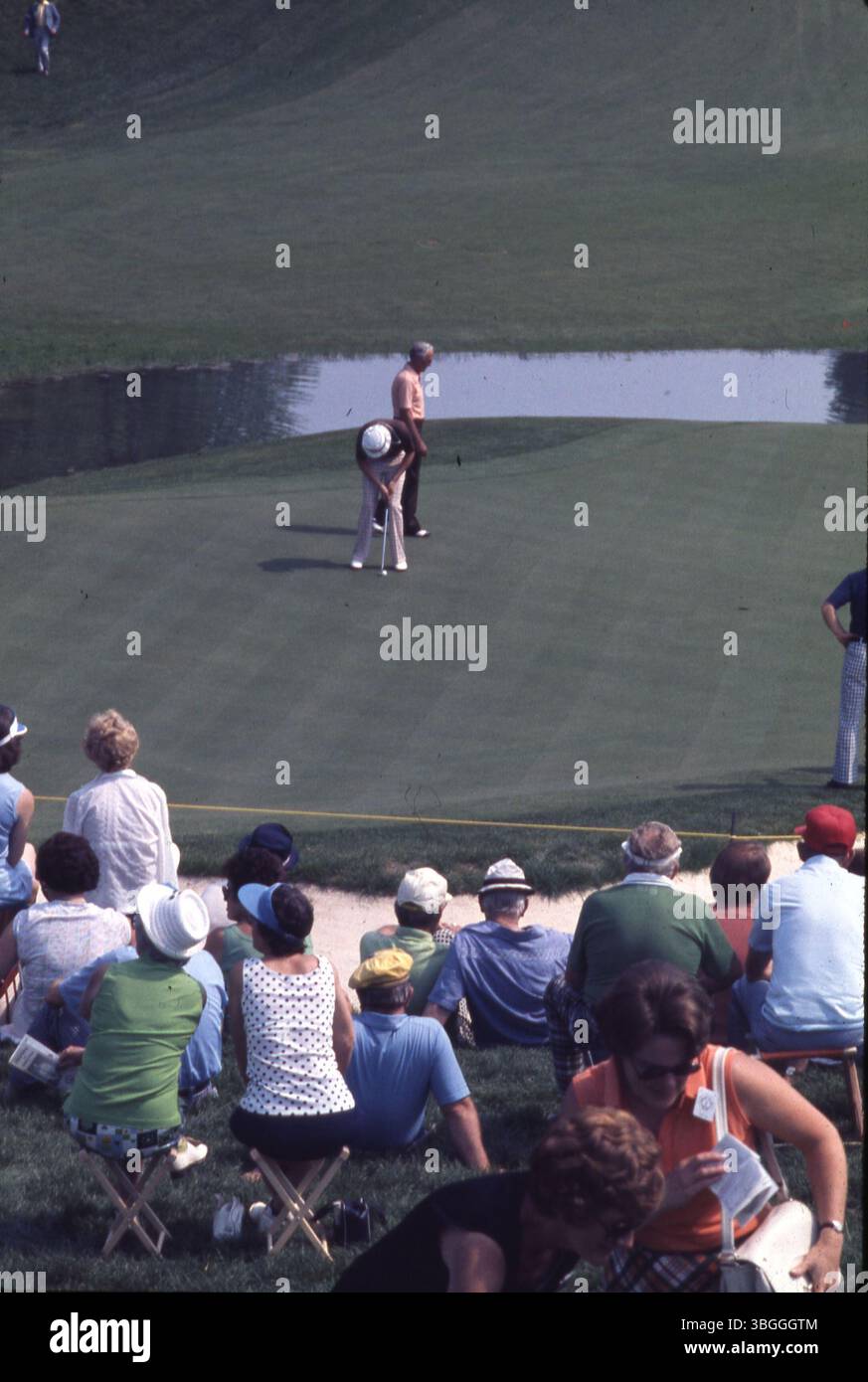 Zwei nicht identifizierte Golfspieler auf einem Putting Green während des Memorial Tournament 1977 pro-am im Muirfield Village Golf Club, mit Zuschauern hinter einem Seil und einer Sandfalle im Blick. Stockfoto
