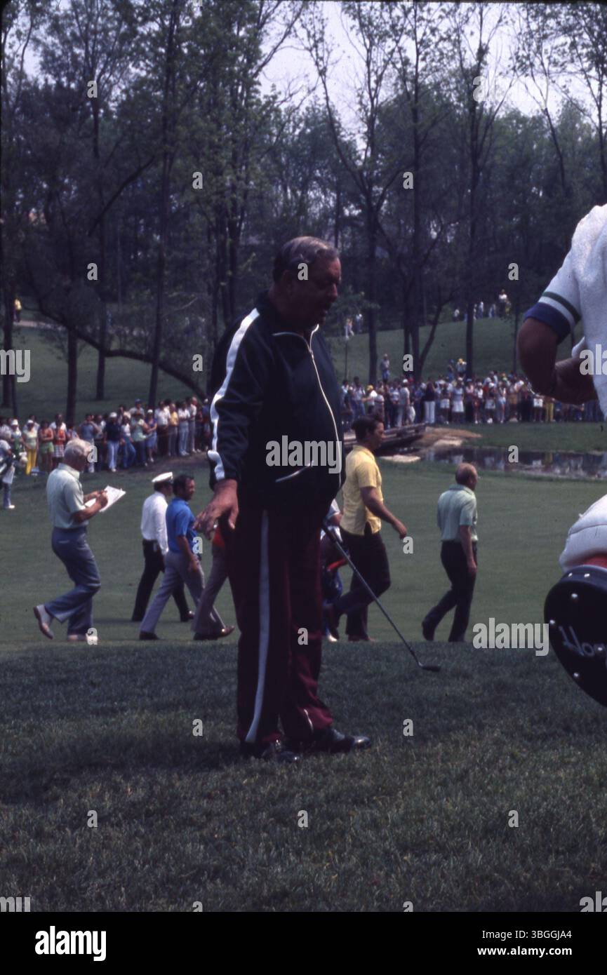 Schauspieler Jackie Gleason spaziert mit einem Eisen in der Hand während des Memorial Tournament pro-am 1977 entlang des Platzes. Gleason spielte an der Seite von Gerald Ford, Jack Nicklaus, Bob Hope und Glen Campbell, mit Zuschauern im Hintergrund. Stockfoto