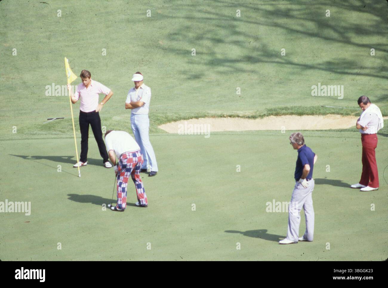 Fünf nicht identifizierte Golfspieler sind auf dem Green während des Memorial Tournament pro-am 1984 im Muirfield Village Golf Club zu sehen. Ein Golfer bereitet sich auf den Putt vor, während ein anderer den Flaggenstock hält, der die Atmosphäre dieses jährlichen Wohltätigkeitsevents veranschaulicht. Stockfoto