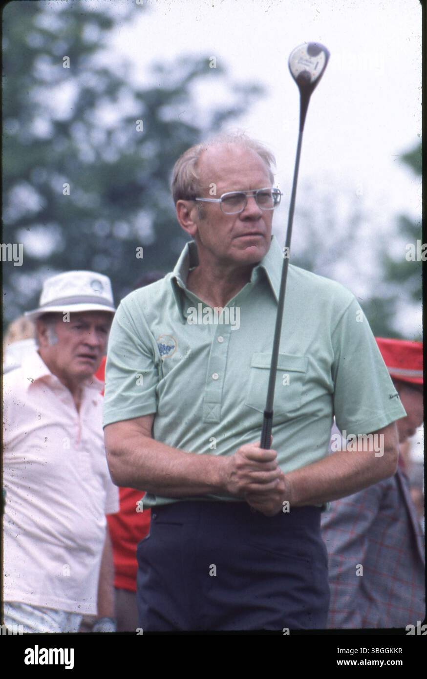 Der ehemalige Präsident Gerald Ford hält während des Memorial Tournament 1977 einen Golfclub pro-am im Muirfield Village Golf Club. Hinter ihm steht der Komiker Bob Hope. Sie waren Teil einer sechsköpfigen Gruppe, zu der die Golfspieler Jack Nicklaus und Roger Maltbie, der Komiker Jackie Gleason und der Musiker Glen Campbell gehörten. Stockfoto
