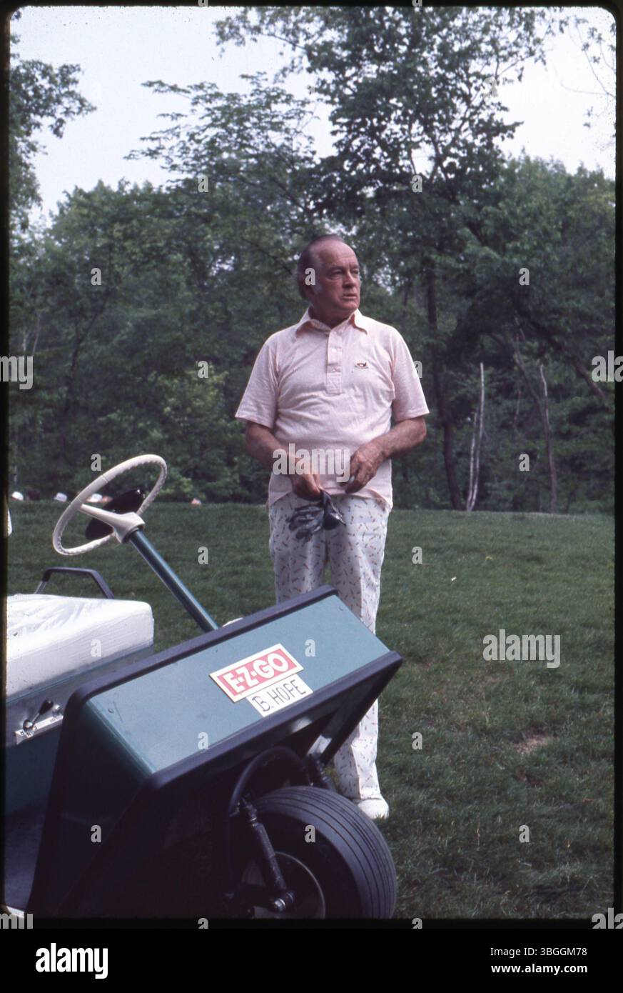 Der Schauspieler und Komiker Bob Hope steht während des Memorial Tournament Pro-am 1977 im Muirfield Village Golf Club in der Nähe eines Golfwagens. Hope spielte neben prominenten Persönlichkeiten wie Präsident Gerald Ford, den Golfspielern Jack Nicklaus und Roger Maltbie, dem Schauspieler Jackie Gleason und dem Musiker Glen Campbell. Stockfoto