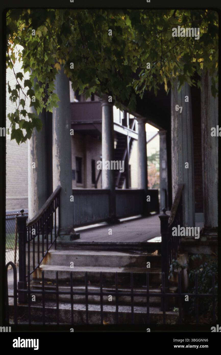 Ein Blick auf eine Veranda auf einem nicht identifizierten Gebäude, gestützt von hohen Säulen mit der Zahl 67 auf einer Säule. Stockfoto