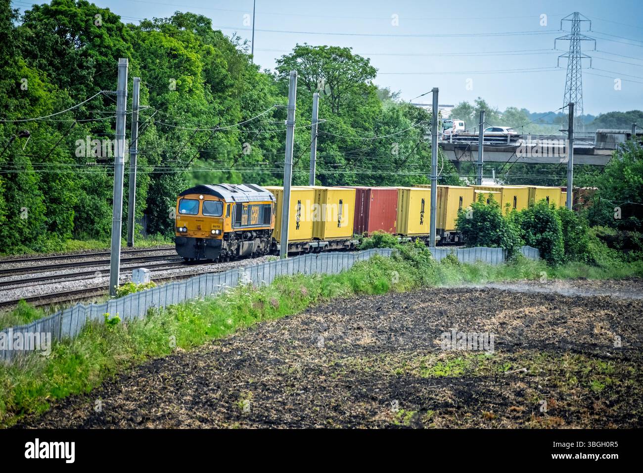 Die dieselelektrische Güterlokomotive der GBRf-Güterklasse 66 mit dem Namen Blue Lightning, die Container auf der Westküste-Hauptstrecke in Winwick transportiert. Stockfoto