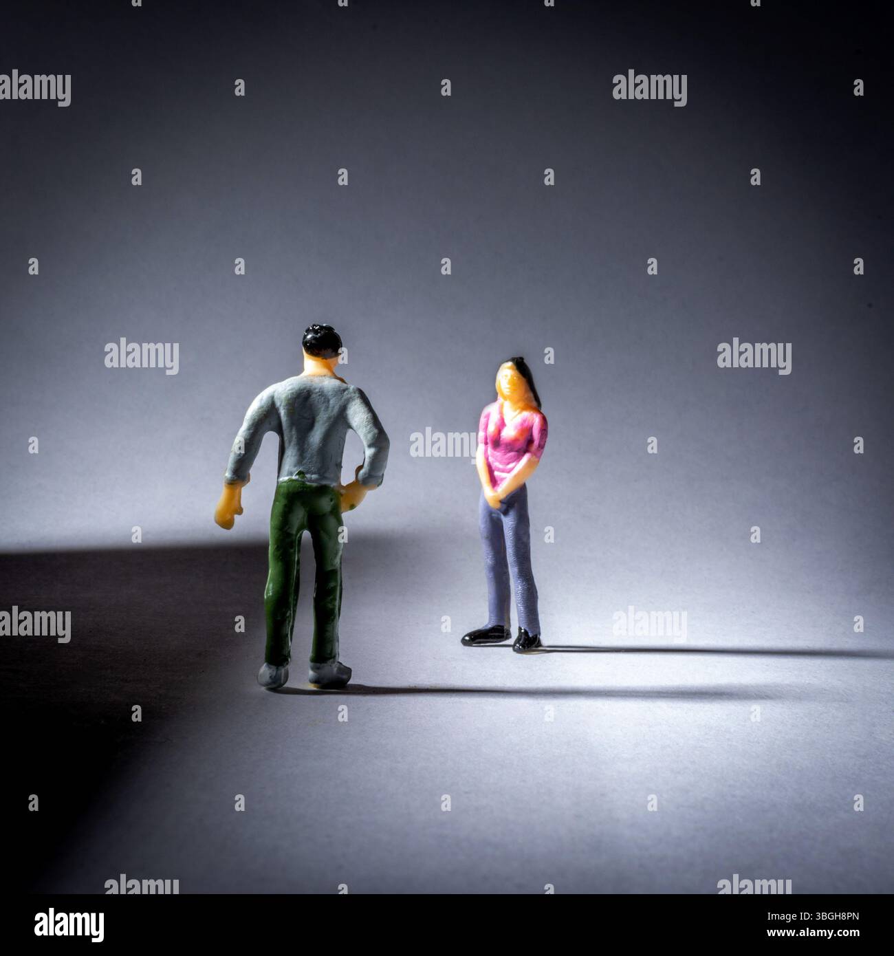 Zwei kleine Figuren führen ein Gespräch, wobei der Schwerpunkt auf ihrer Körpersprache liegt. Die Beleuchtung erzeugt einen Schatteneffekt, der die Interaktion hervorhebt. Stockfoto