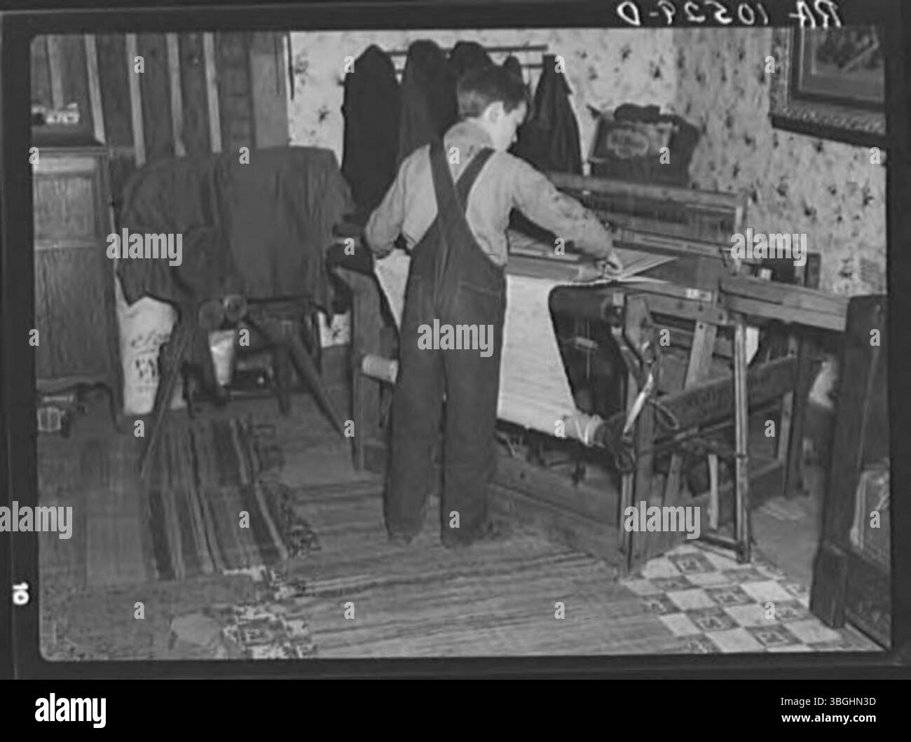 Ein Sohn von Erasty Emvich, einem Pächter mit zwölf Kindern, wird in seinem Bauernhaus beim Weben eines Teppichs gesehen. Bei dieser Aktivität wird der landwirtschaftliche Lebensstil der Familie neben traditionellem Kunsthandwerk wie Weberei vorgestellt. Stockfoto