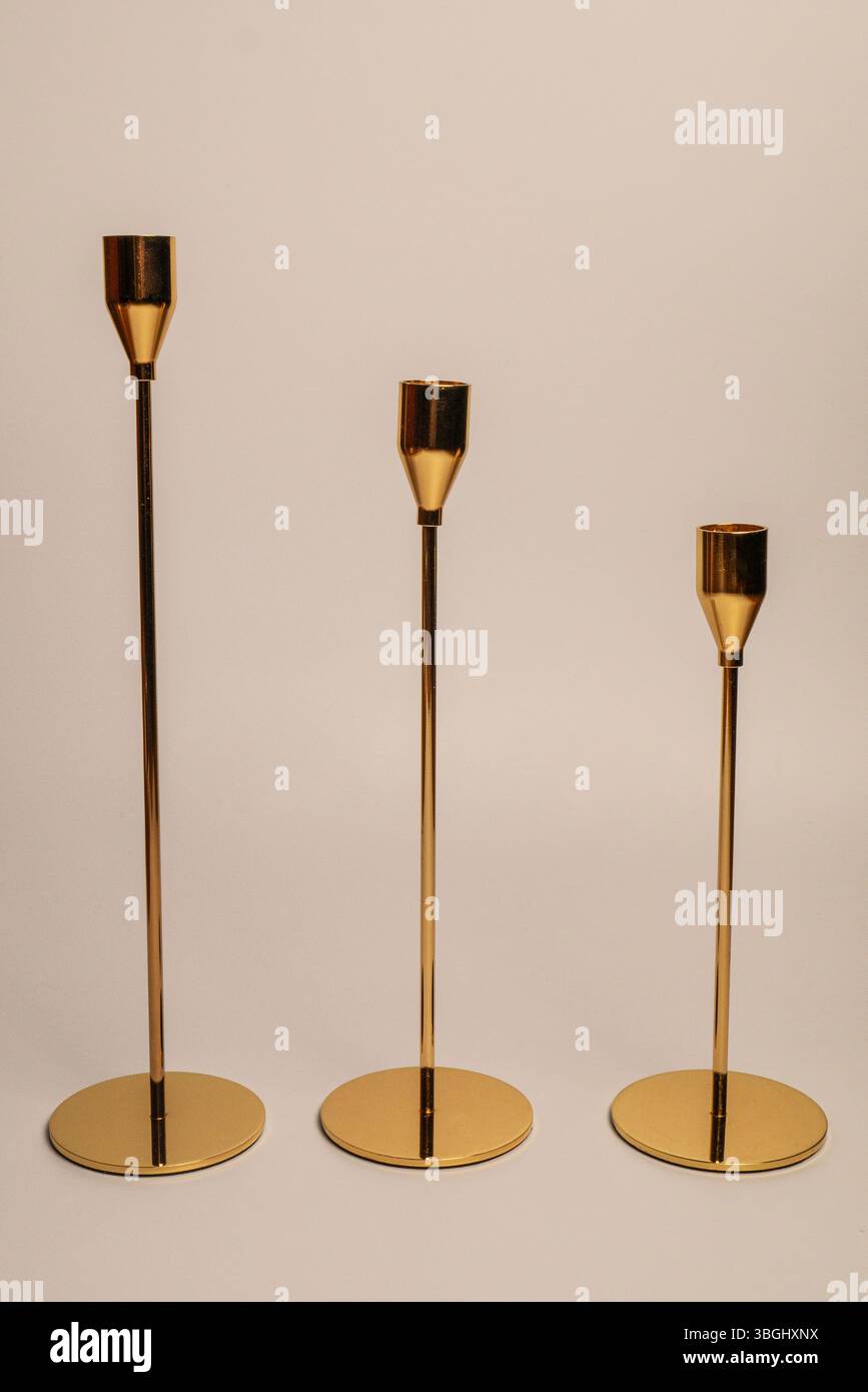 Set aus drei minimalistischen goldenen Kerzenleuchtern mit schlanken, dünnen Beinen und runden, flachen Untergründen auf weißem Hintergrund. Stockfoto Set aus drei minimalistischen goldenen Kerzenleuchtern mit schlanken, dünnen Beinen und runden, flachen Untergründen auf weißem Hintergrund. Stockfoto