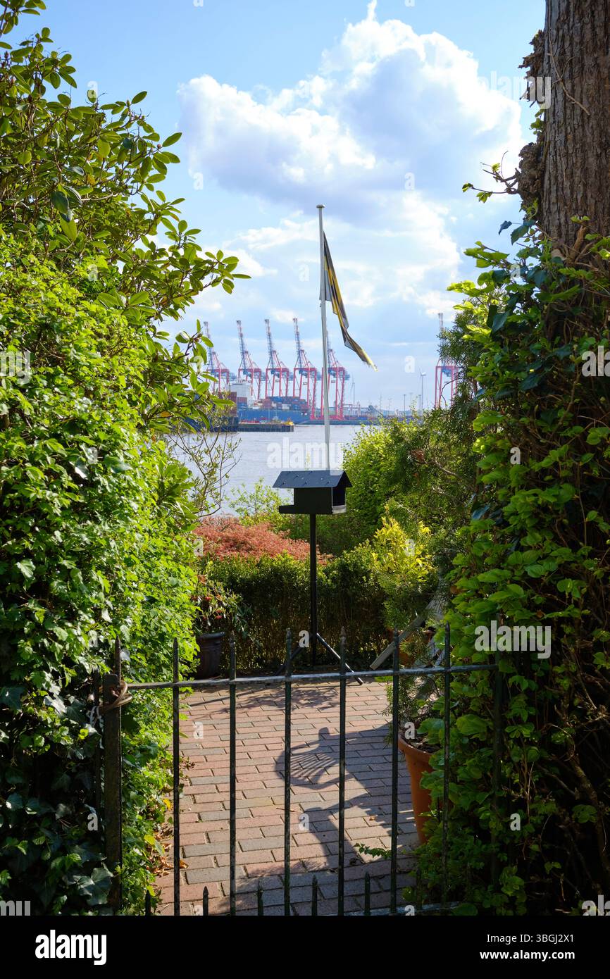 Vogelhaus und schwenkende Flagge auf einer Terrasse an der Hamburger Elbstrand-Promenade. Die Elbe und Teile des Containerhafens sind im Hintergrund zu sehen Stockfoto