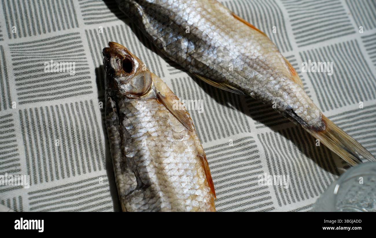 Getrockneter Fisch auf gemusterter Tischdecke – traditioneller osteuropäischer Snack Stockfoto