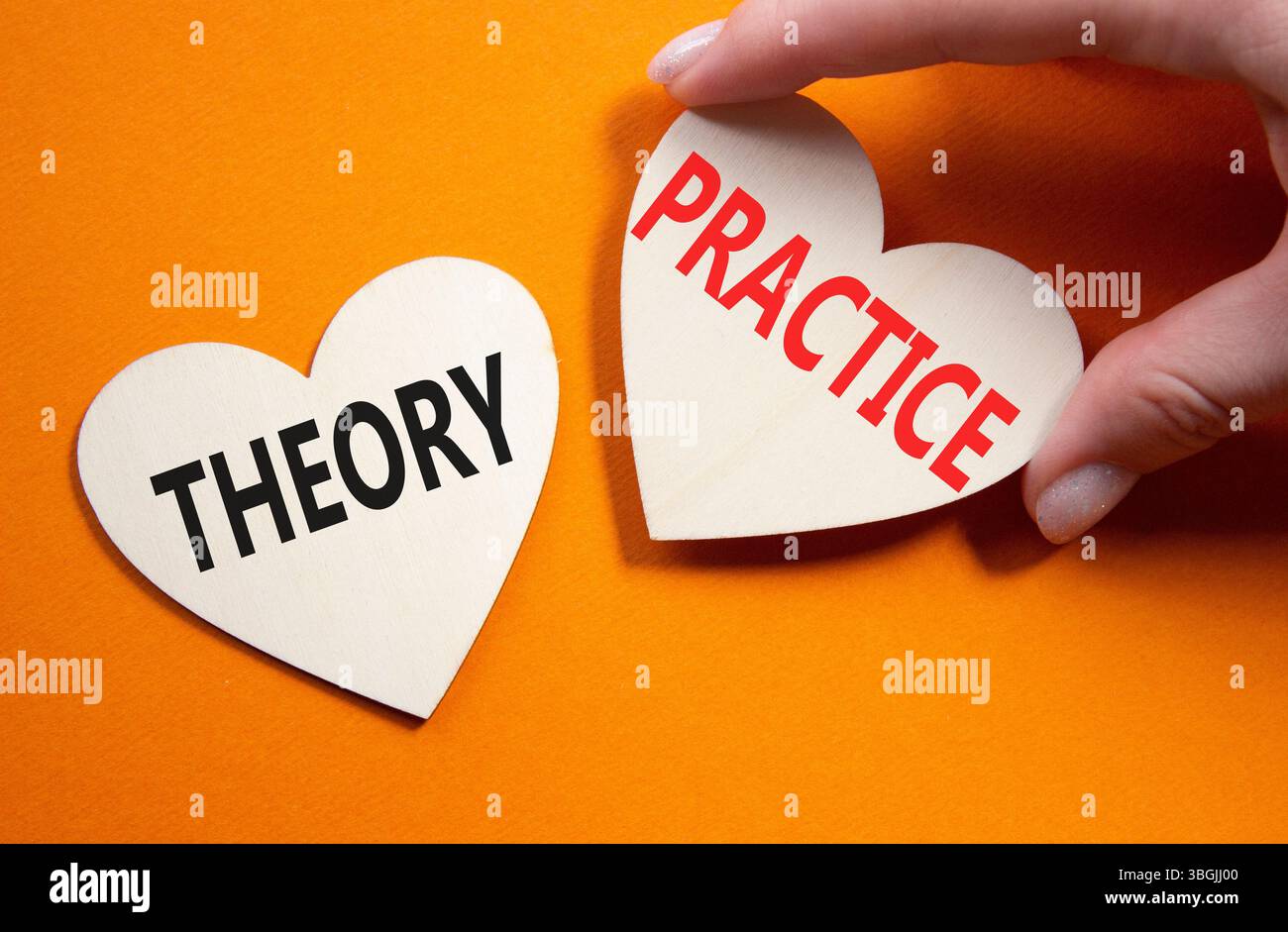 Theorie- oder Praxissymbol. Konzeptwort Theorie oder Praxis auf hölzernen Herzen. Geschäftsmann Hand. Wunderschöner orangefarbener Hintergrund. Business and Theory oder Pra Stockfoto