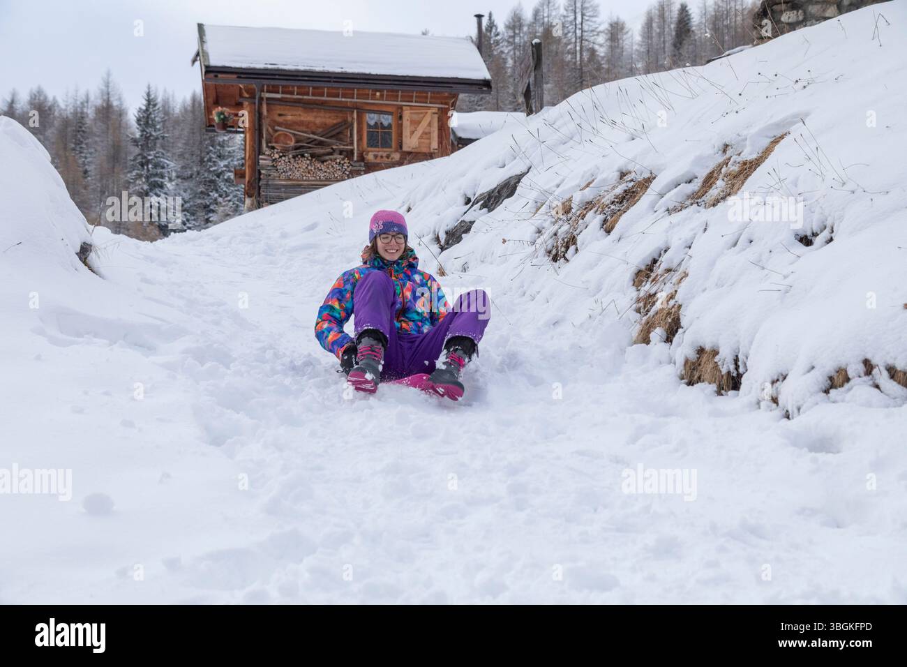 Teen Girl fährt auf frischem Schnee, lacht und genießt einen lustigen Wintertag in heller Sportbekleidung Stockfoto