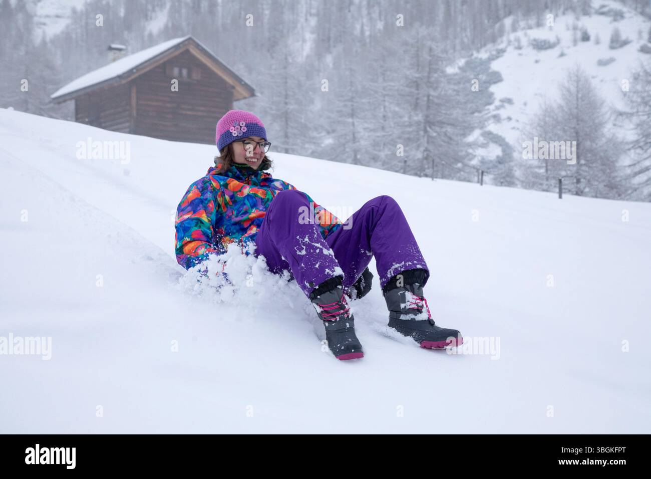 Teen Girl fährt auf frischem Schnee, lacht und genießt einen lustigen Wintertag in heller Sportbekleidung Stockfoto