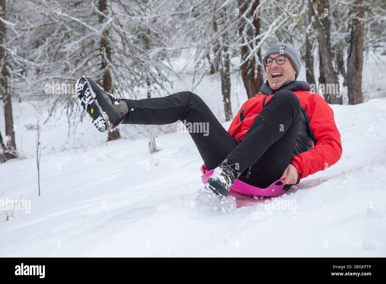 Reifer Mann, der mit farbenfroher Sportbekleidung auf Schnee fährt und einen Wintertag voller Spaß und Spannung genießt Stockfoto