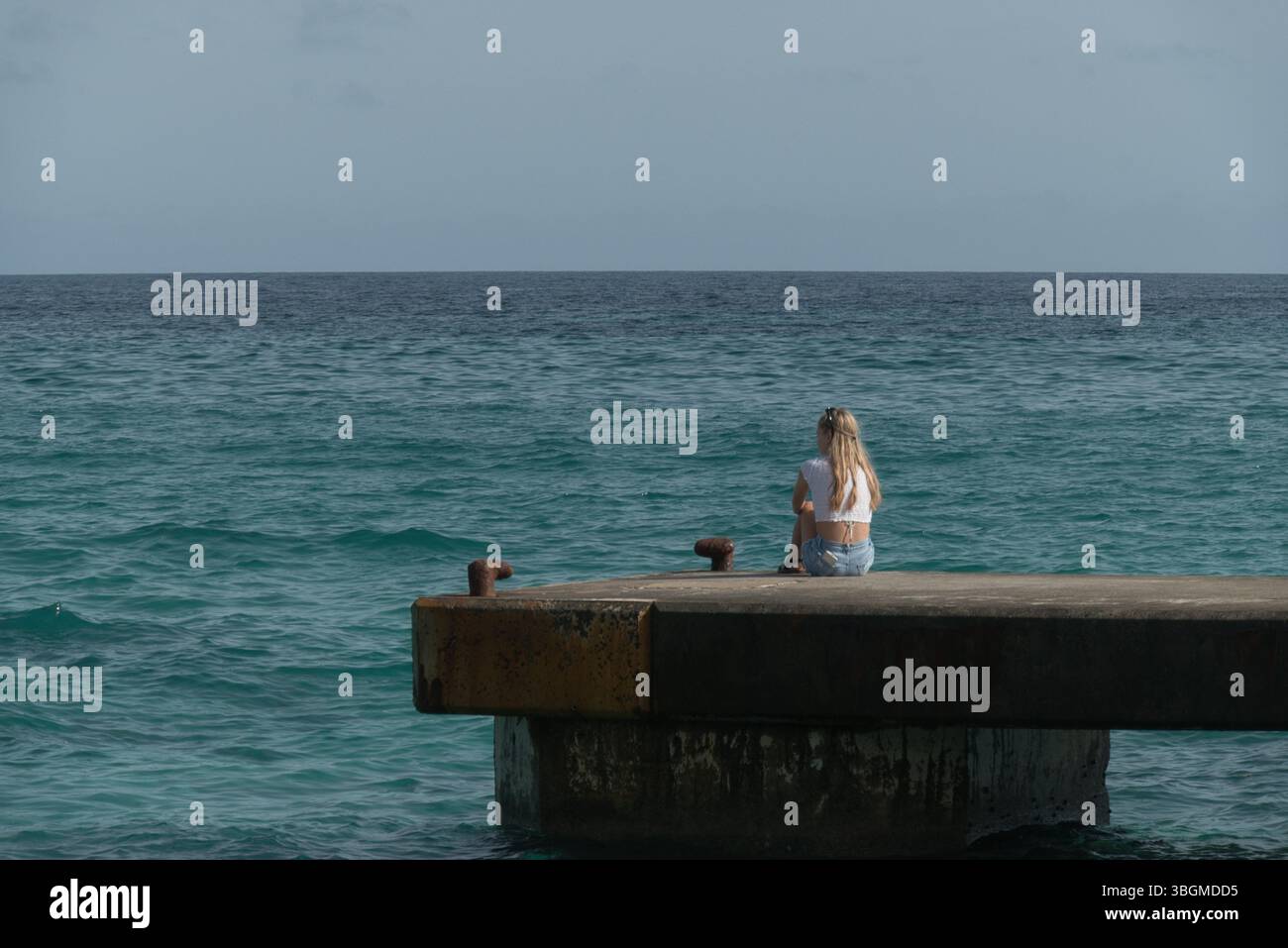 'Einsamer Moment auf einem ruhigen Pier - Reflexionen am Wasser Stockfoto